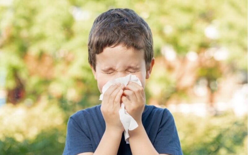 Chłopiec z katarem na tle drzew