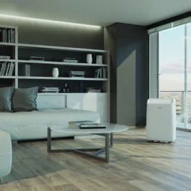 Klimatyzator przenośny Whirlpool PACF212CO W ustawiony w salonie z dużym oknem. Materiały producenta Whirlpool